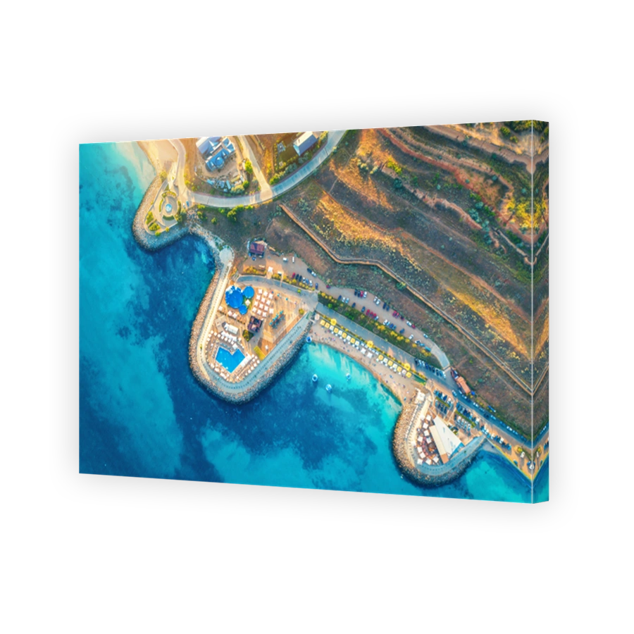 Aerial view of beautiful sandy beach, blue sea, restaurants on the promenade, pool, umbrellas, swimming people in clear water, green trees at sunset in summer. Top view of seafront. Tropical landscape