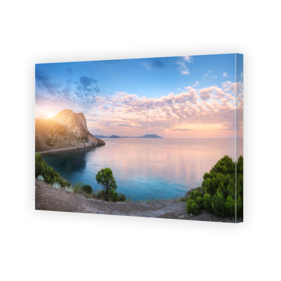 Summer landscape at sunset. Green trees against the sea, mountains and blue sky with clouds and sunlight. Travel and nature background. Colorful evening landscape. Vacations. Park in crimean mountains