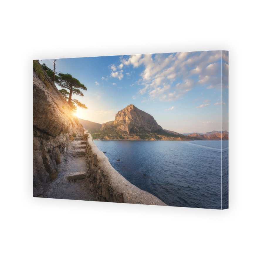 Summer landscape with mountain path, rocks, trees growing out of the cliff, blue sea and blue sky with clouds at sunset. Nature background. Beautiful trail through the mountain. Travel in Crimea