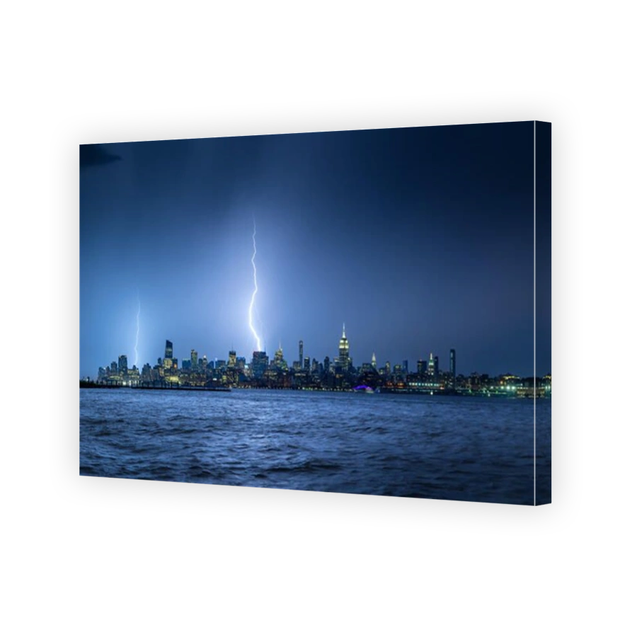 Lightning striking New York City skyscrapers at night. Stormy skies over Midtown West Manhattan from the Hudson River