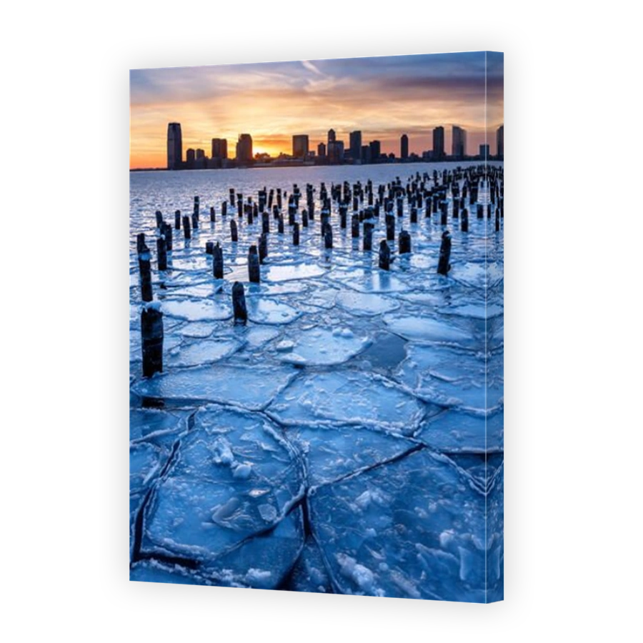 Winter skyline of the Frozen Hudson River with old wood pilings at sunset with Downtown Jersey City skyscrapers