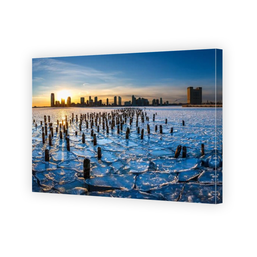 Sunset on the frozen Hudson River with old wood pilings and view on Downtown Jersey City, New Jersey