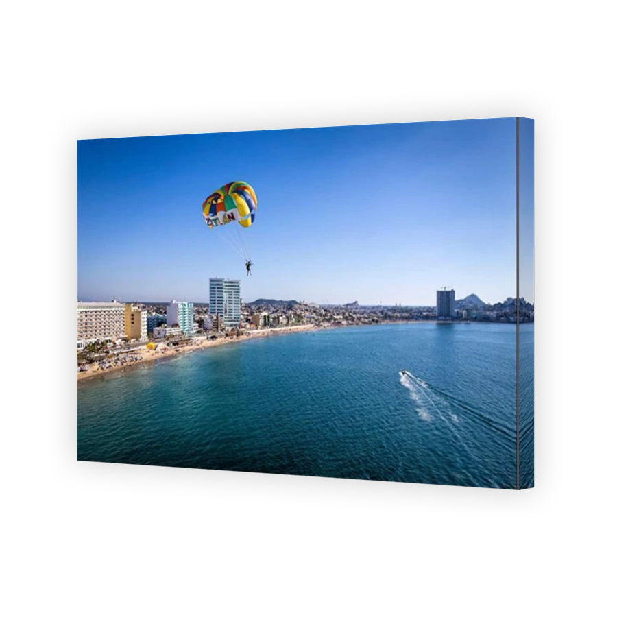 A parasailer glides over the ocean near the beach and malecon of Mazatlan, Sinaloa, Mexico.