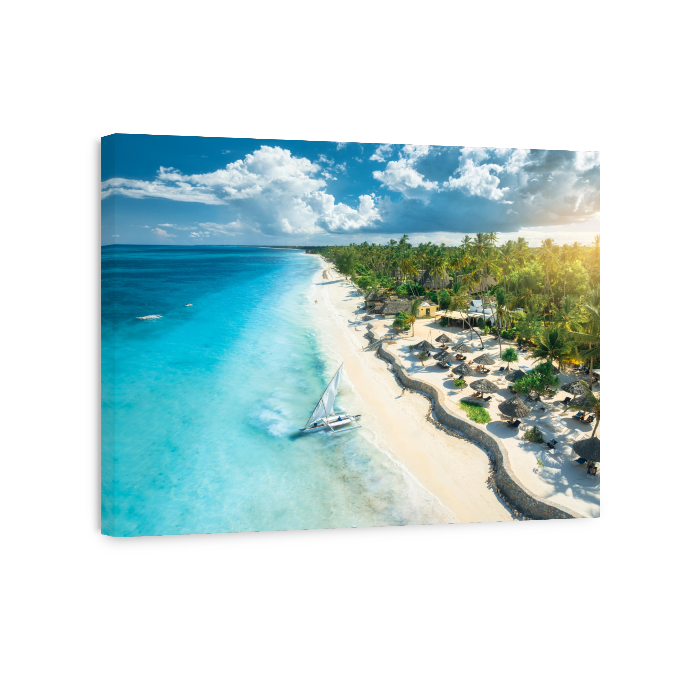 Aerial view of the sailboat on blue sea, empty white sandy beach, umbrellas at sunset. Summer in Zanzibar. Tropical scenery with boat, ocean with waves, green palms, sky. Top drone view. Exotic