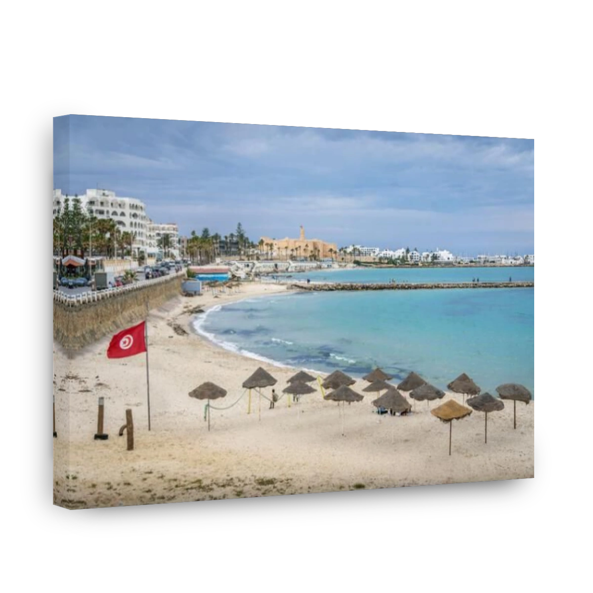 The beach and Mediterranean sea coastline at resort town of Monastir, Tunisia, with the long pier, Tunisian flag, umbrellas, waterfront, and Raban (ca