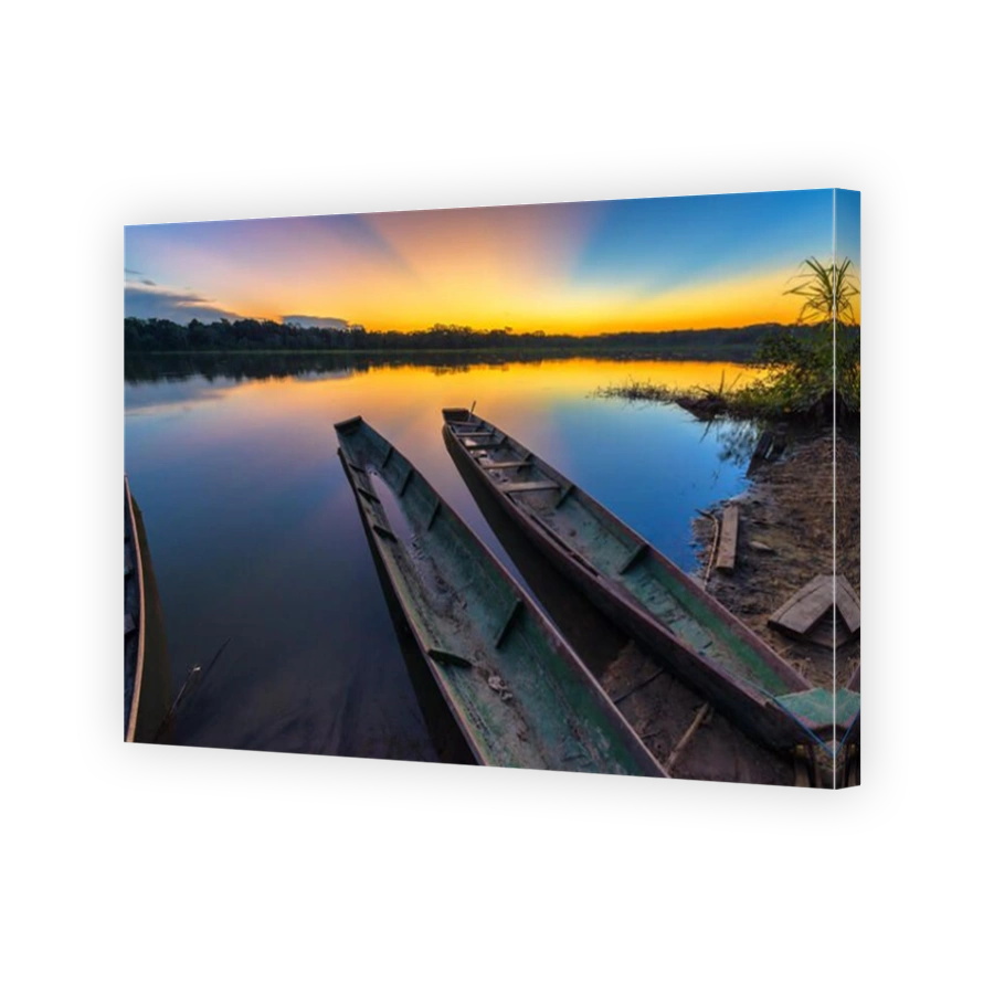 Dramatic sunset in the Amazon rain forest in Bolivia in Madidi National Park with two canoes in the foreground