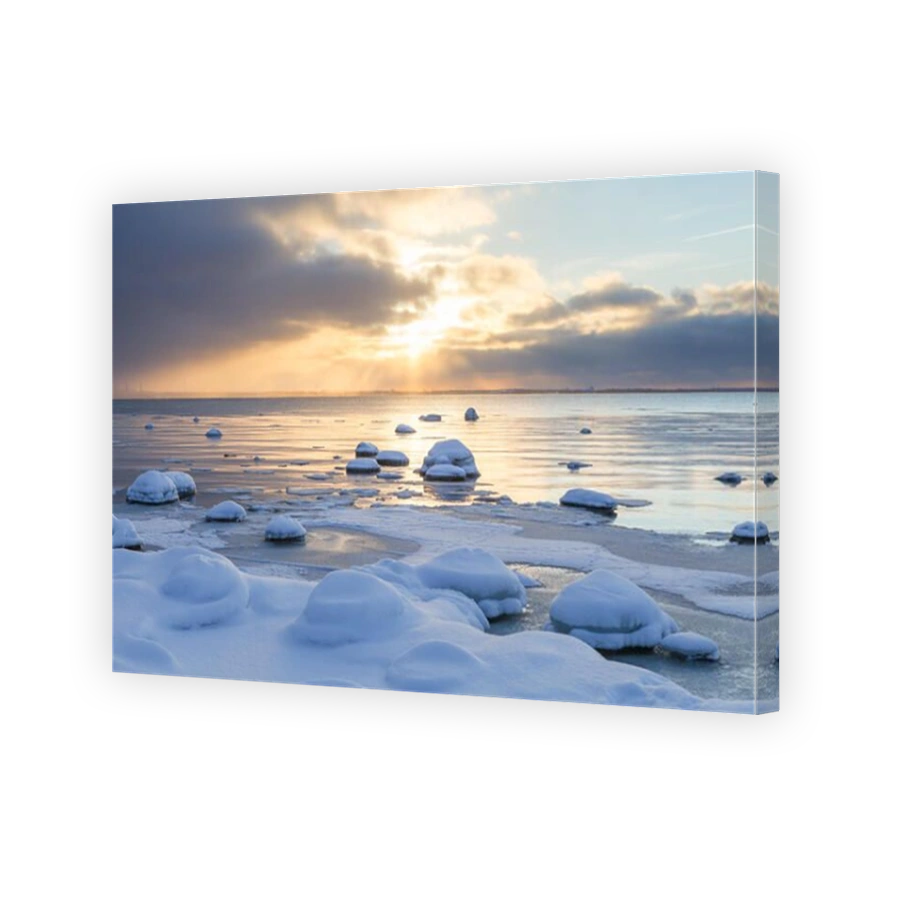 Sunset with snowy boulders and beach landscape. Baltic sea, winter time.