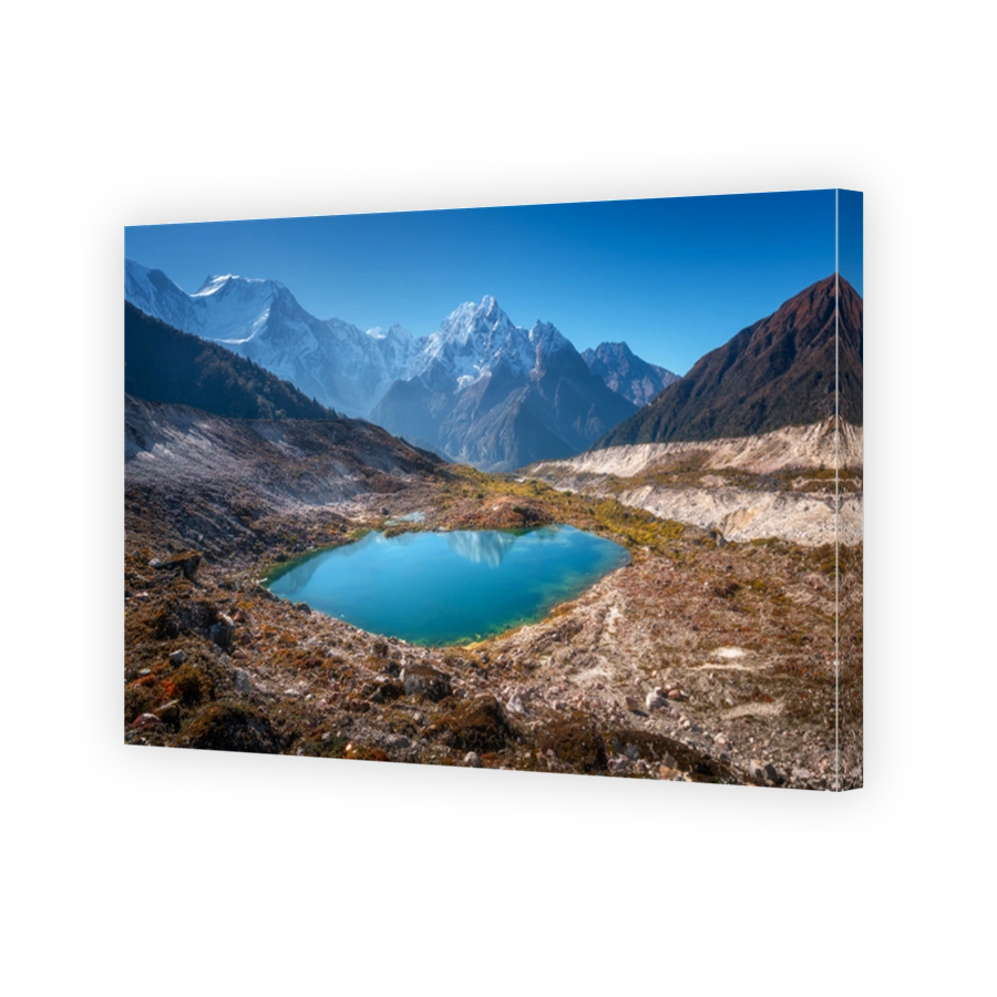 Landscape with lake, snowy rocks, hills, stones at sunrise. Himalayan mountains in Nepal