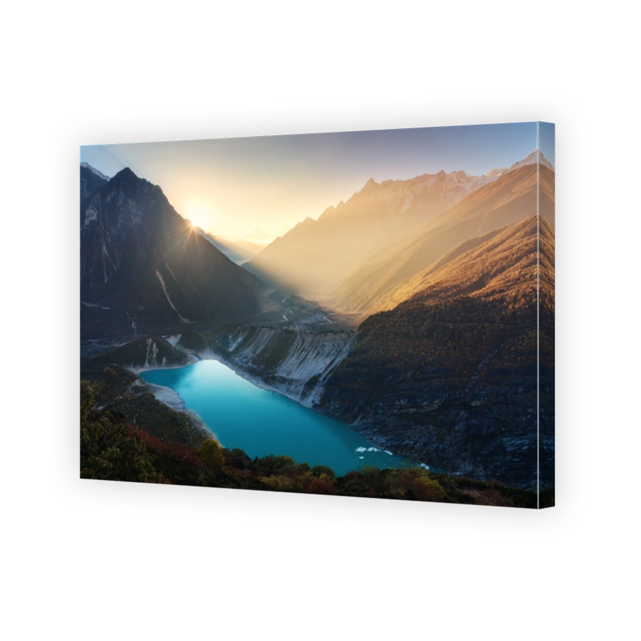 Mountain valley and lake with turquoise water at sunrise in Nepal. Majestical landscape with high mountains, lake, lightened hills, rocks, sun with yellow light and sky. Bright sunny morning. Travel