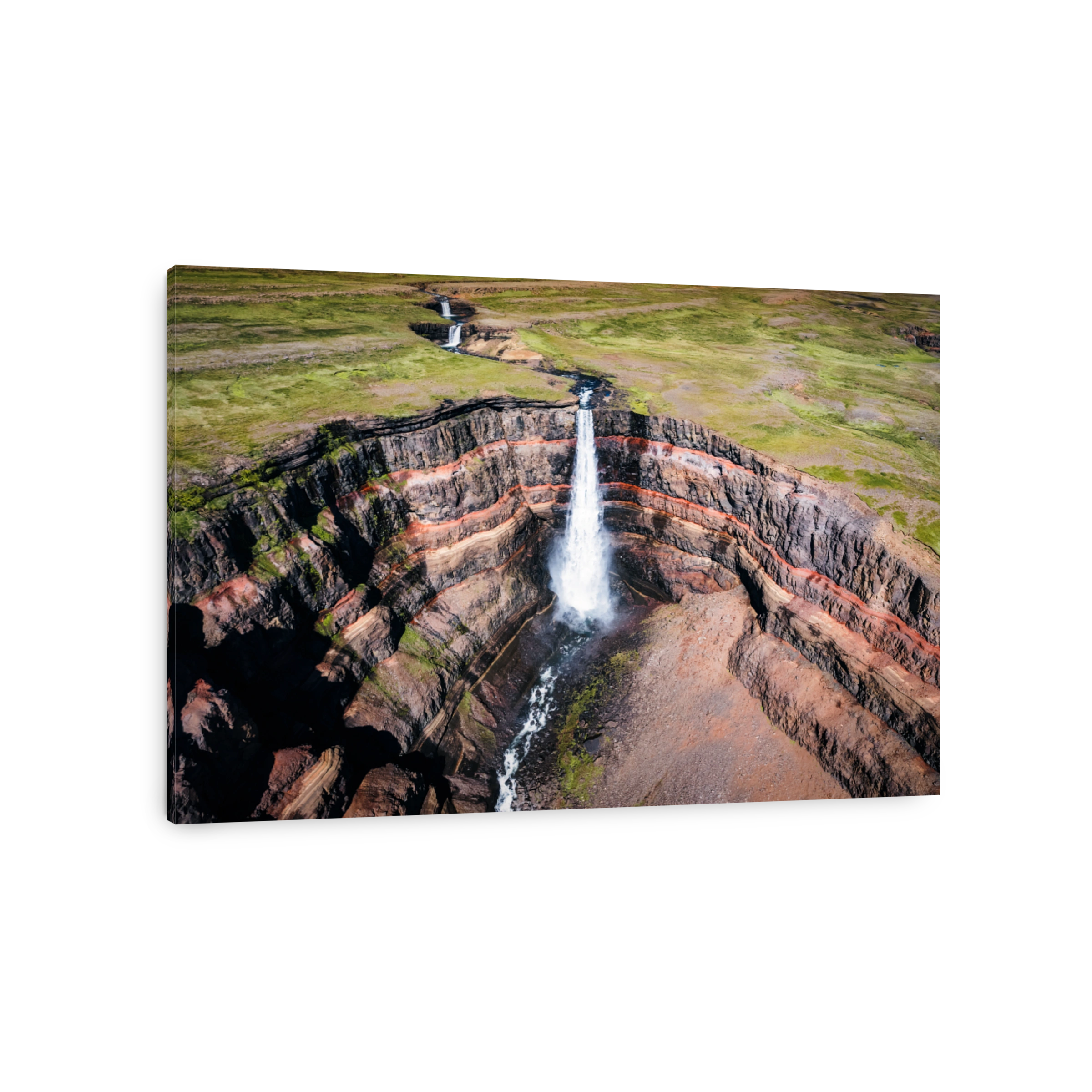 Hengifoss waterfall surrounded by layers of basaltic strata with water flowing in summer at Iceland