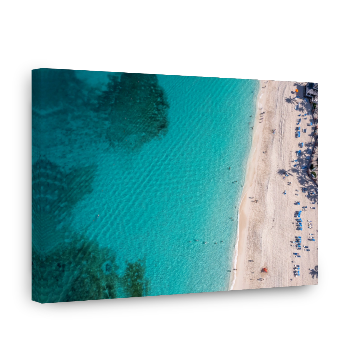 Aerial view of an emerald and transparent Caribbean sea with a white beach full of beach umbrellas and tourists.