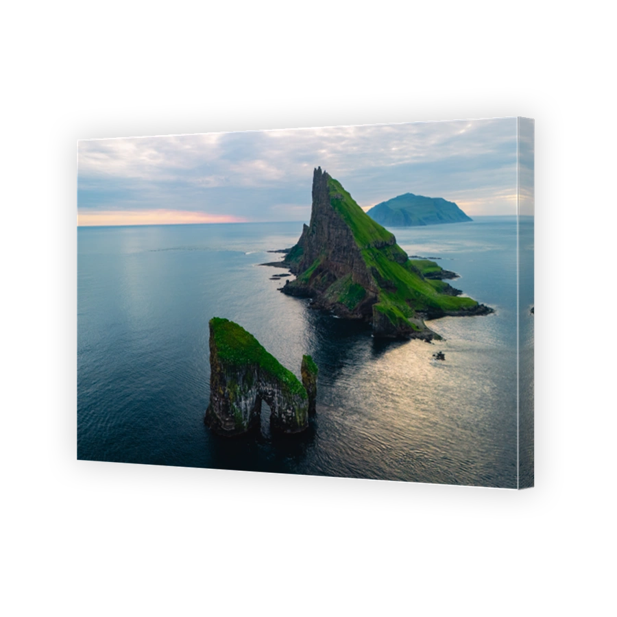 Majestic rock formations rise from tranquil waters in the Faroe Islands at dusk