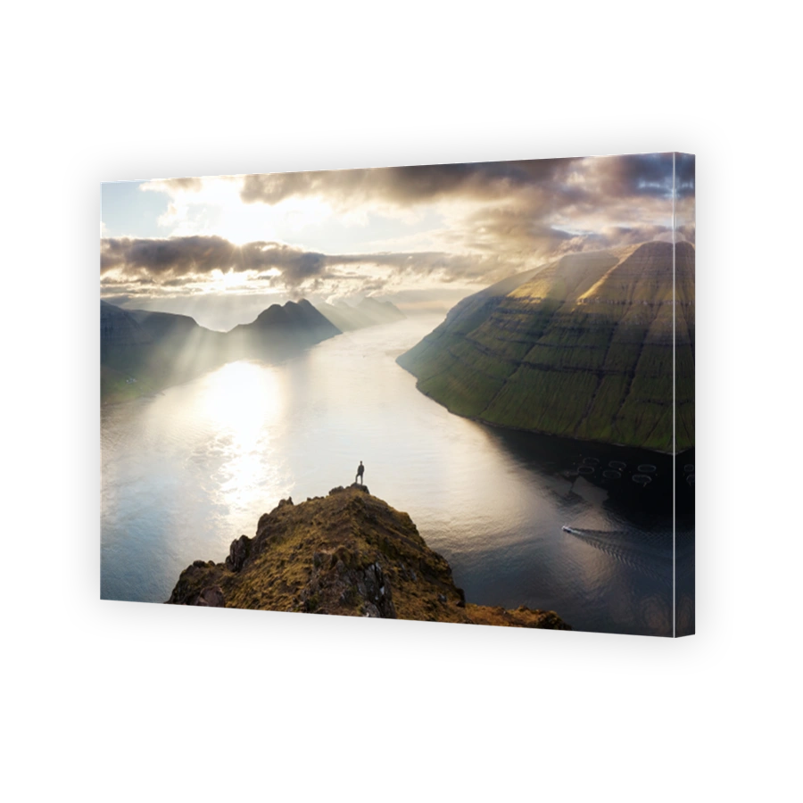 Silhouette of man over dramatic sunset with mountain and ocean in Faroe islands near Klaksvik