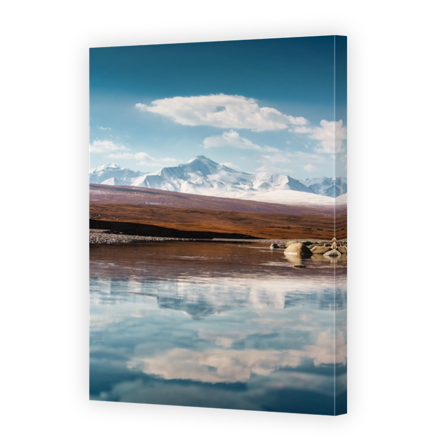 Tian Shan snow covered mountain peak and reflective lake on sunny day at Sary jaz remote valley