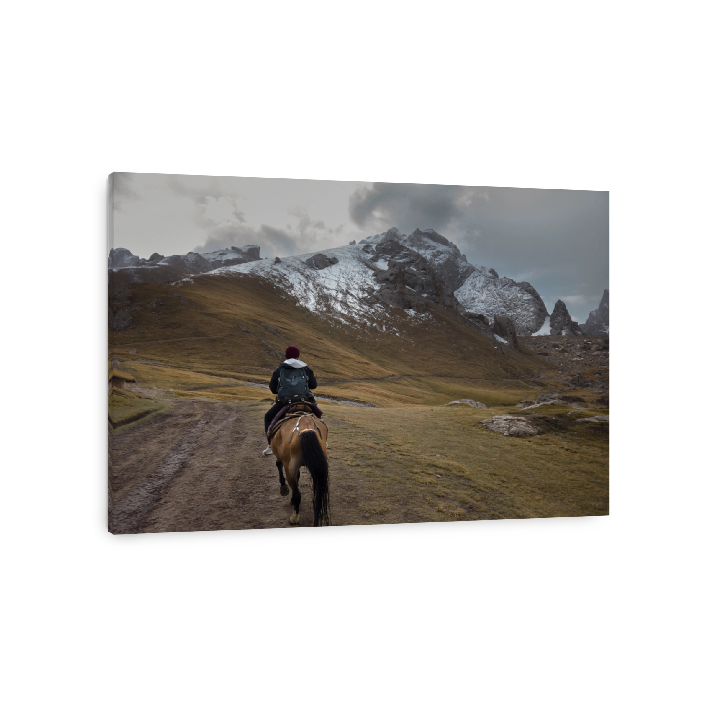 A solo female traveler riding a horse in the remote area of snowcapped Tien Shan mountain range