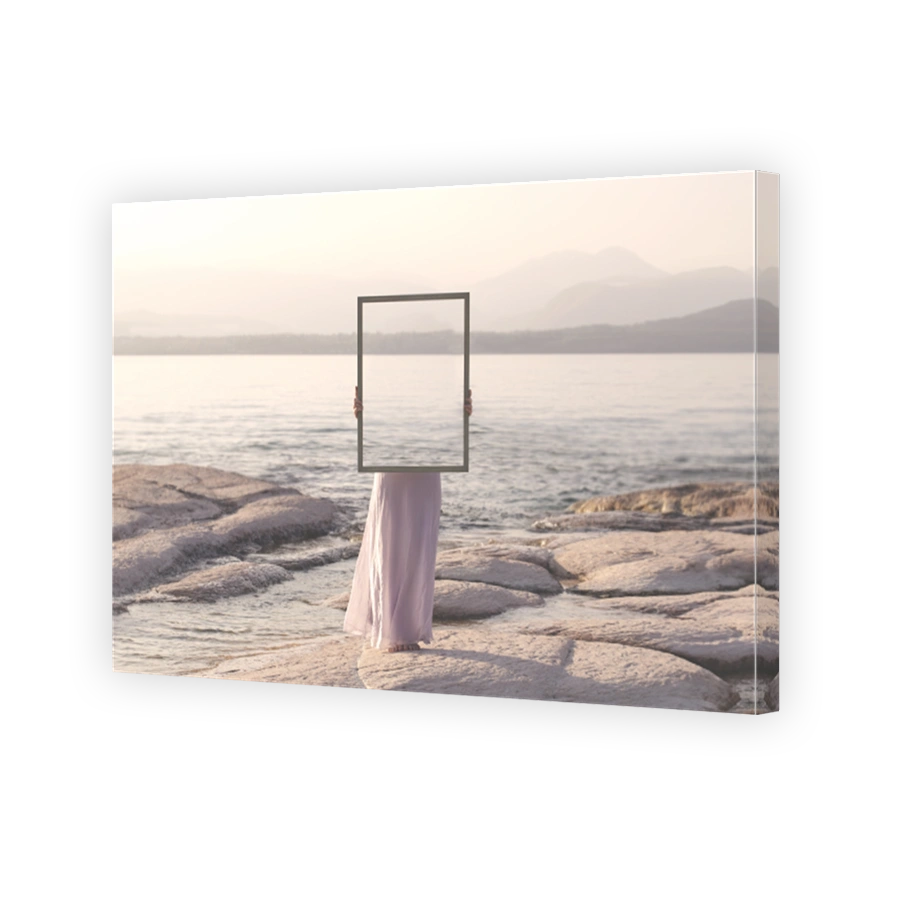 woman holding a frame that surreally reflects the landscape , abstract concept