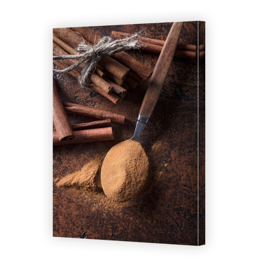Cinnamon sticks and powder in spoon on a old copper table .