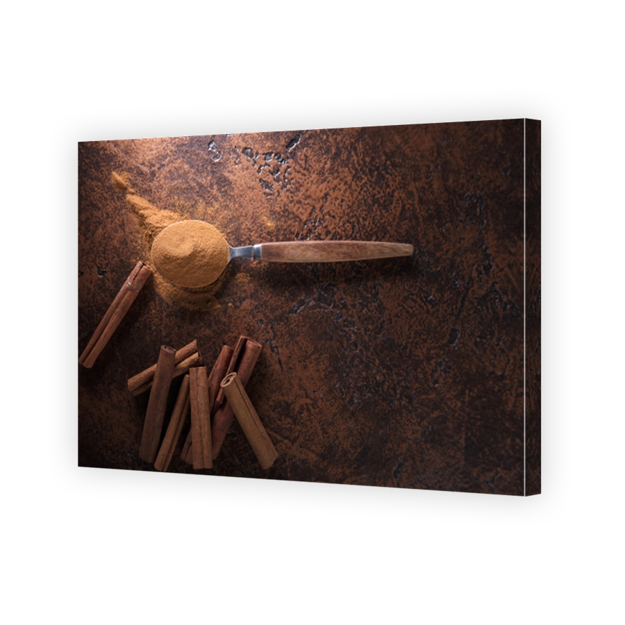 Cinnamon sticks and powder in spoon on a old copper table .
