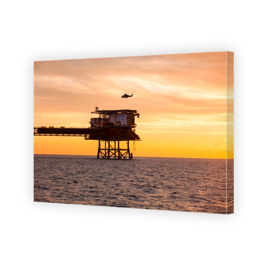 Helicopter is landing on an offshore oil installation during sunset