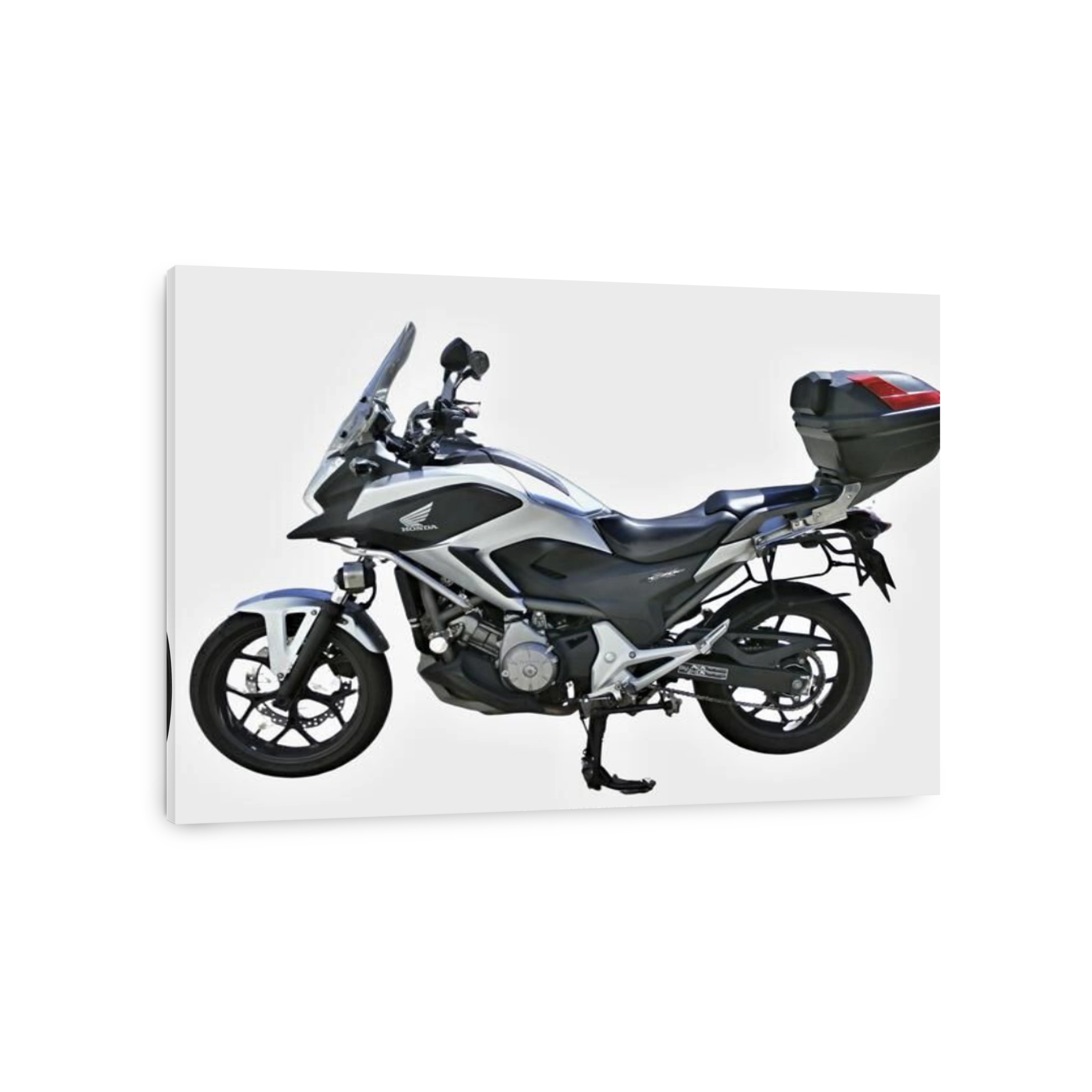 Studio shot of a silver Honda NC700X motorcycle with luggage, isolated on white background