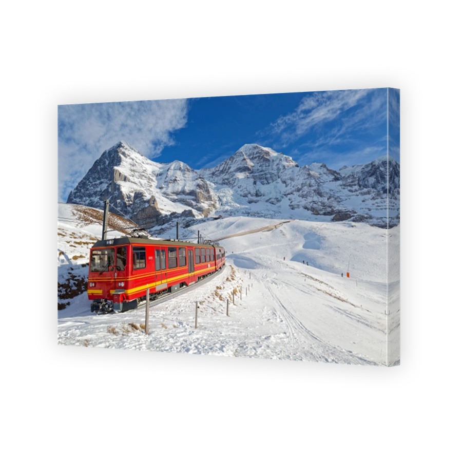 On a sunny winter day, tourists ride on a cogwheel train from Jungfraujoch (Top of Europe) to Kleine Scheidegg on the snowy hillside with Eiger and Monch in background, in Berner Oberland, Switzerland