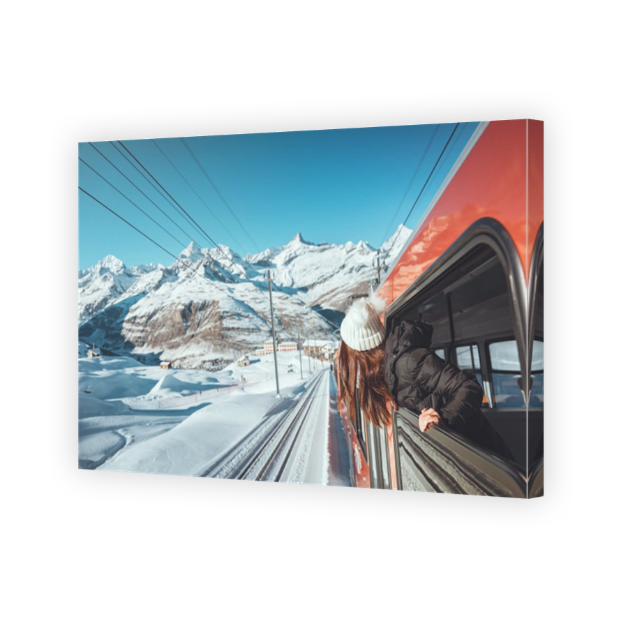 Happy woman traveler looks out from window traveling by train in beautiful winter mountains, Travel concept.