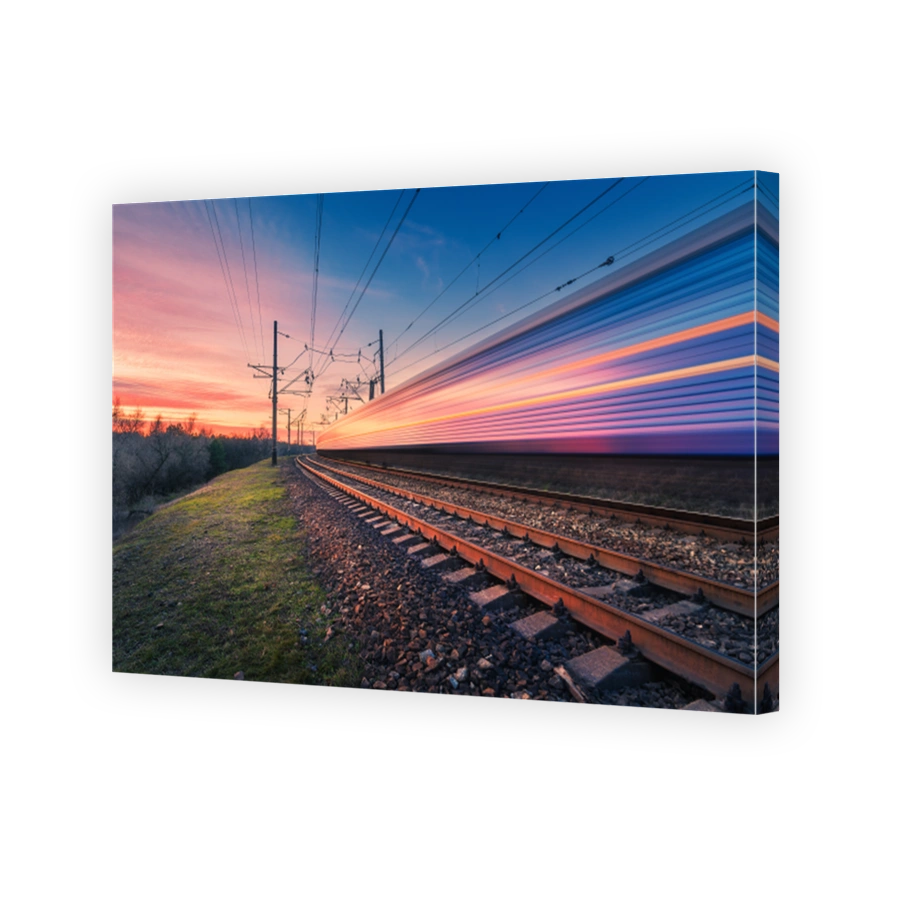 High speed passenger train in motion on railroad at sunset. Blurred modern commuter train. Railway station and colorful sky. Railroad travel, railway tourism. Industrial landscape. Transportation