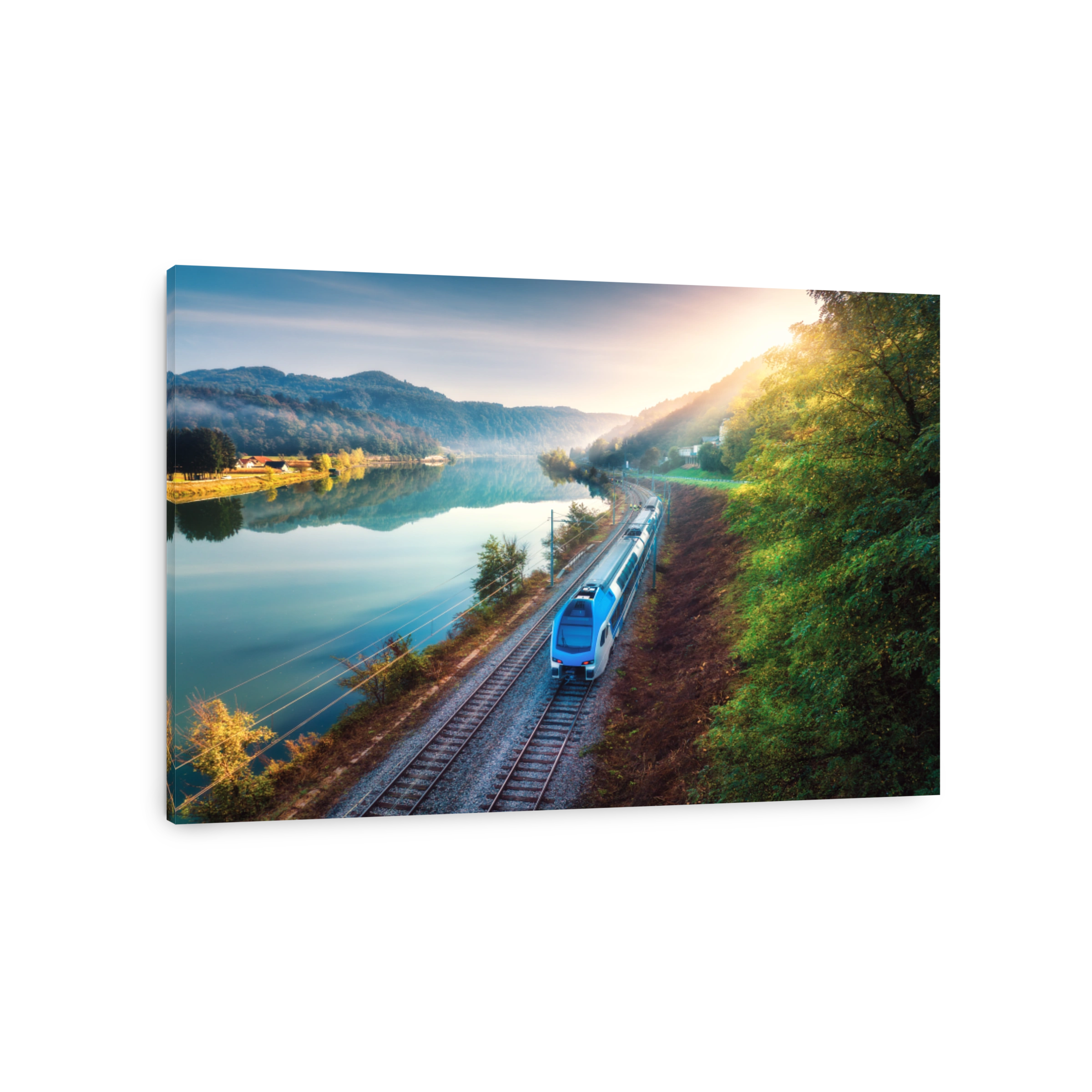 Aerial view of blue modern high speed train moving near river in alpine mountains at sunrise in summer. Top view of train, railroad, lake, reflection, trees in spring. Railway station in Slovenia