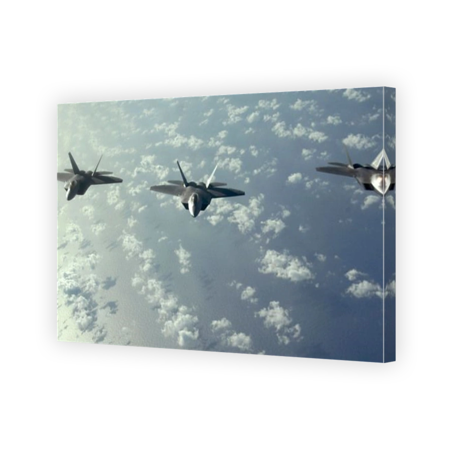 A three-ship formation of F-22 Raptors fly over the Pacific Ocean during a Pacific theater mission.