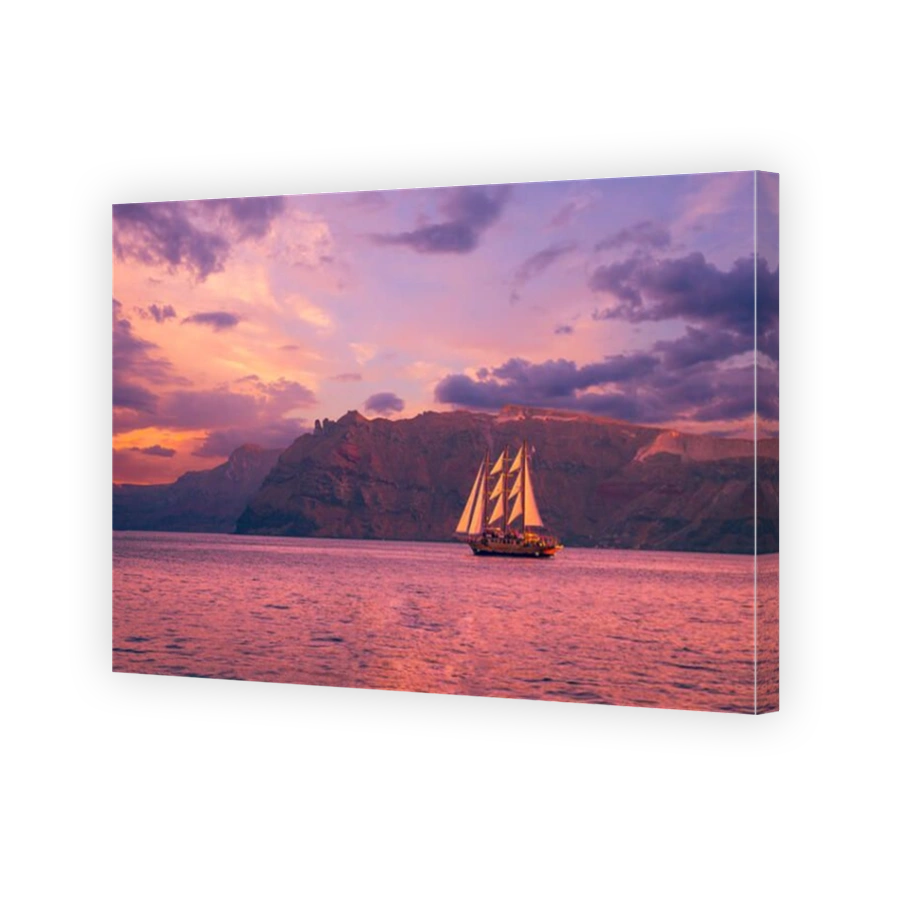Sailboat in Santorini, Greece. Sailing ship navigate near an island in Cyclades. The photo is taken at sunset.
