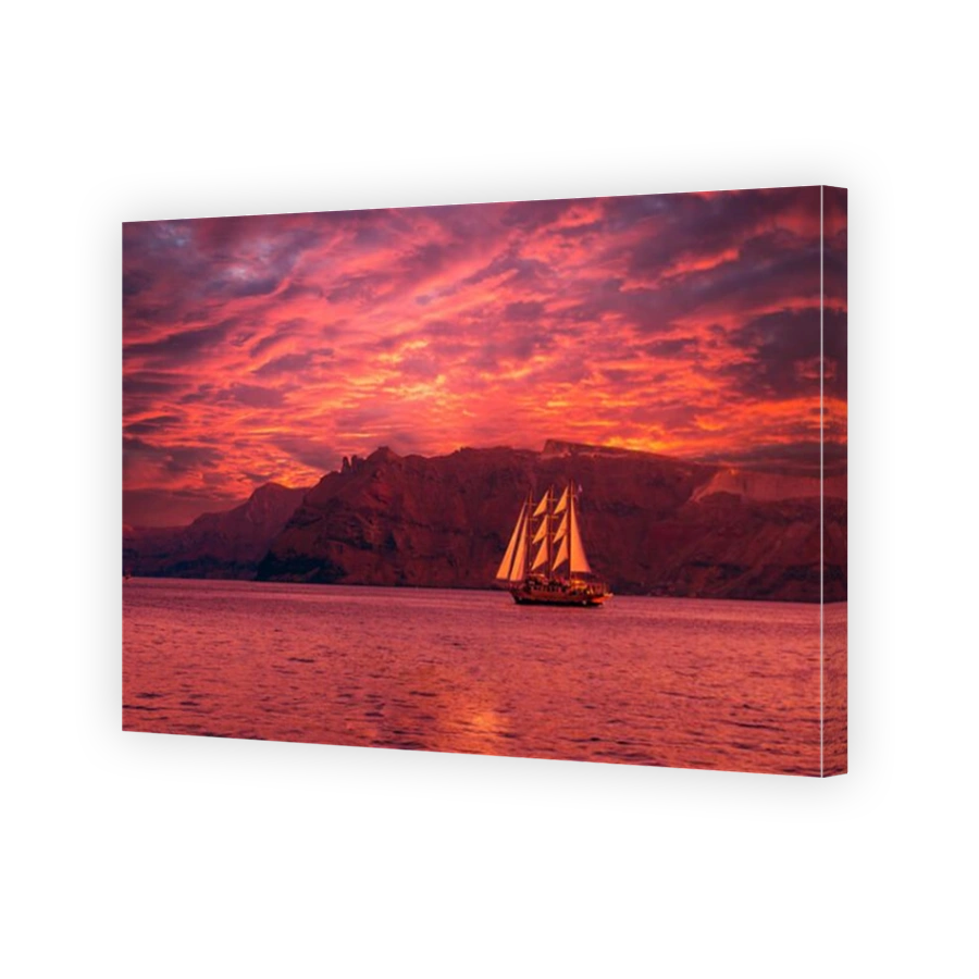 Sailboat in Santorini, Greece. Sailing ship navigate near an island in Cyclades. The photo is taken at sunset.