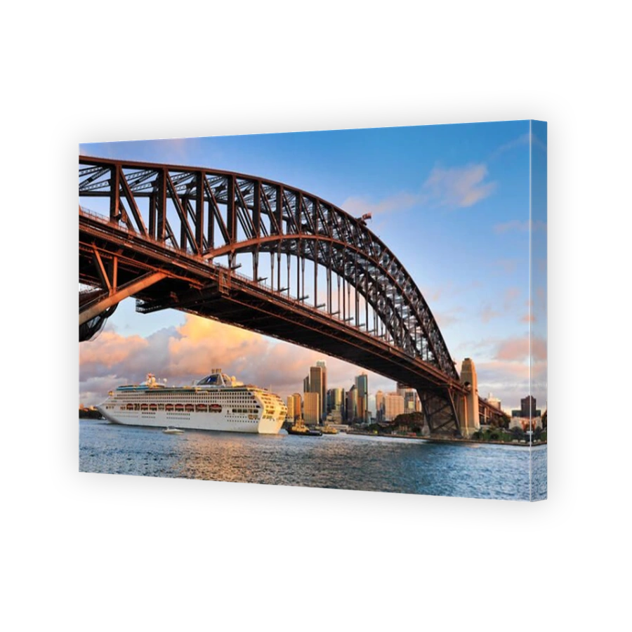 Oversized ocean cruise liner passing by under the Sydney Harbour Bridge at sunset backgrounded by city skyscrapers